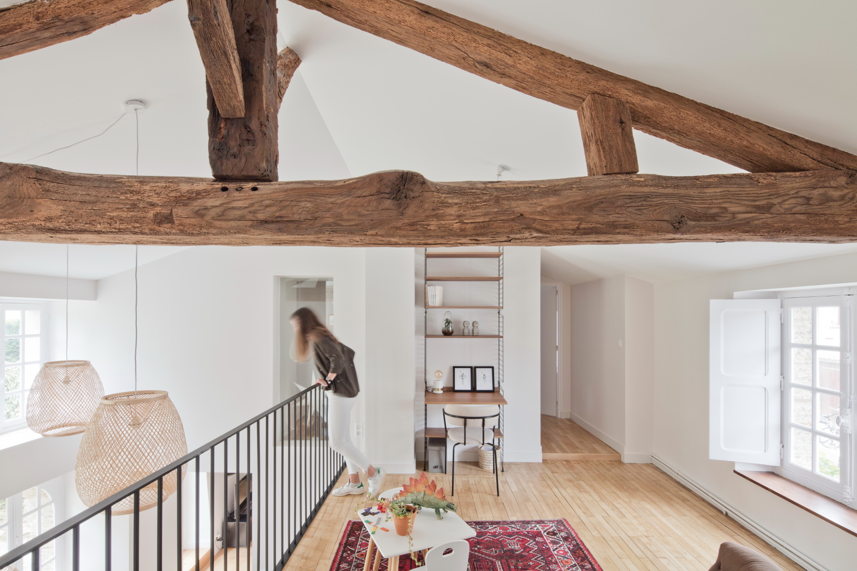 Réhabilitation d'une maison par une agence d'architecture, avec des poutres anciennes apparentes et un garde corps en fer noir
